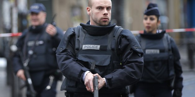 Police officers secure the perimeter near the scene of a fatal shooting which took place at a police station in Paris, Wednesday, Jan. 7, 2016. French officials say a man armed with a knife was shot to death by officers at a police station in northern Paris. Two officials say the man had wires extending from his clothing, and an explosives squad is on site. (AP Photo/Christophe Ena)