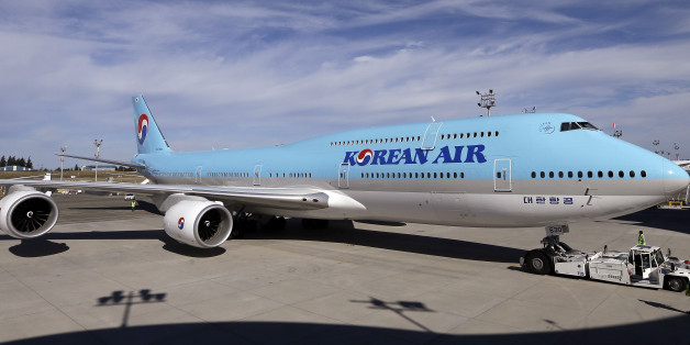 As another plane flies overhead, a Boeing 747-8 Intercontinental jet is moved into position for a delivery ceremony to Korean Air, Tuesday, Aug. 25, 2015, in Everett, Wash. The jet is the first of 10 of the passenger airplanes the carrier has on order with Boeing. With the delivery, Korean Air becomes the first airline to operate both passenger and freighter versions of the 747-8. (AP Photo/Elaine Thompson)