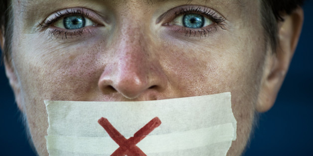 The girl with tape sealed her mouth white on adhesive tape drawn cross with a red marker.