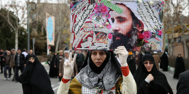 An Iranian worshipper holds up a poster showing Sheikh Nimr al-Nimr, a prominent opposition Saudi Shiite cleric who was executed by Saudi Arabia, as she shows victory sign while attending an anti-Saudi protest rally after the Friday prayers in Tehran, Iran, Friday, Jan. 8, 2016. Thousands of worshippers who took part in Friday prayers in Tehran joined the rally, carrying pictures of al-Nimr and chanting "Death to Al Saud," referencing the kingdom's royal family. Iranian state media reported simi