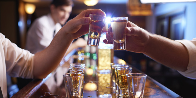 Customer and bartender toasting with shot glasses