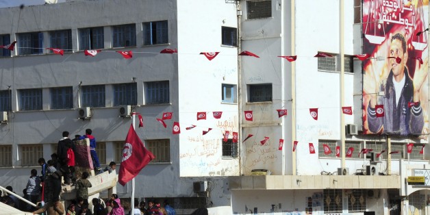 Tunisian gather in Sidi Bouzid, Tunisia, Thursday, Dec.17, 2015 to mark the fifth anniversary of the Tunisian unrest. Tunisians who won the Nobel Peace Prize joined townspeople in the country's beleaguered heartland to mark five years since the desperate street vendor, seen on poster at right, set himself on fire, unwittingly setting in motion upheaval across the Arab world. (AP Photo/Hassene Dridi)