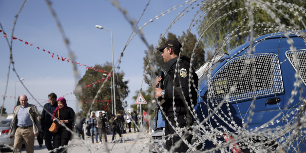 People walk by as as a police officer guards the National Bardo Museum in Tunis, Tunisia, Thursday, March 19, 2015. Tunisian security forces arrested nine people linked to the deadly attack on the National Bardo Museum that left scores dead and wounded and threatened the country's fledgling democracy and struggling tourism industry, the president's office said Thursday. (AP Photo/Christophe Ena)
