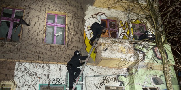 Zwei Polizisten versuchen über eine Leiter in das Haus in der Rigaer Straße zu gelangen