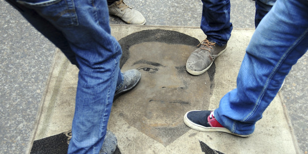 Protestors step on a carpet depicting ousted Tunisian President Zine El Abidine Ben Ali during a demonstration to mark the third anniversary of his departure, Tuesday, Jan. 14, 2014. Three years ago, mass public protests ousted Tunisian President Zine el-Abidine Ben Ali from office. (AP Photo/Hassene Dridi)