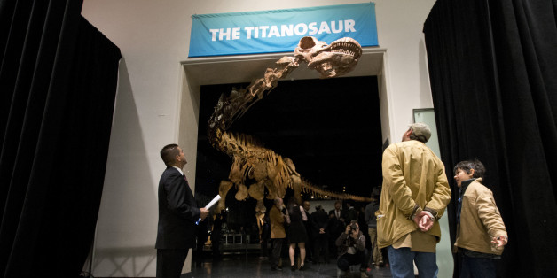 Visitors to the American Museum of Natural History examine a replica of a 122-foot-long dinosaur on display at the American Museum of Natural History in New York, Thursday, Jan. 14, 2016. The dinosaur is a new species and one of the largest dinosaurs ever discovered. It has not yet been formally named by paleontologists who discovered it in Argentina in 2014. It belongs to a group known as titanosaurs. (AP Photo/Mary Altaffer)
