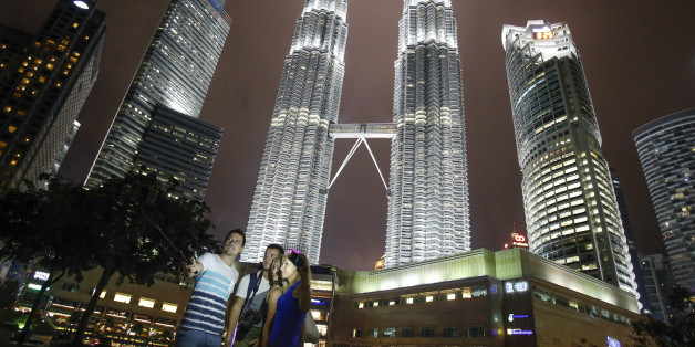 Tourists take souvenir photographs against Malaysia's iconic building, Petronas Twin Towers in Kuala Lumpur, Malaysia, Thursday, Jan. 14, 2016. Malaysia's national police chief Khalid Abu Bakar says police have raised security alert to the highest level following the deadly attack in Jakarta. (AP Photo/Joshua Paul)