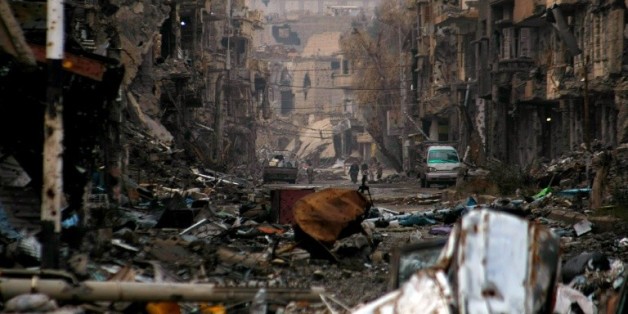 Syrians walk along a severely damaged road in the northeastern city of Deir Ezzor on January 4, 2014. Syrian rebels have united to kill and capture dozens of jihadists in a new "revolution" against an Al-Qaeda affiliate they accuse of worse abuses than the hated President Bashar al-Assad, activists said.