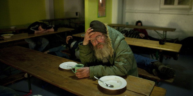Ein obdachloser Mann sitzt in der Kältenotschlafstelle der Evangelischen Stadtmission Berlin zwischen Schlafenden. (AP Photo/Markus Schreiber)