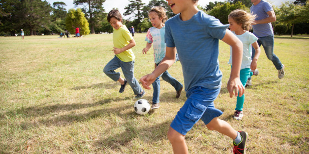 Children, aged 9-10, running together with a soccer ball in a park