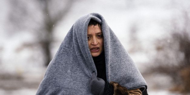 A woman uses a blanket to keep warm as she walks with other migrants and refugees through a snow-covered field after crossing the Macedonian-Serbian border near the village of Miratovac on January 18, 2016.
More than one million migrants reached Europe in 2015, most of them refugees fleeing war and violence in Afghanistan, Iraq and Syria, according to the United Nations refugee agency. / AFP / DIMITAR DILKOFF (Photo credit should read DIMITAR DILKOFF/AFP/Getty Images)