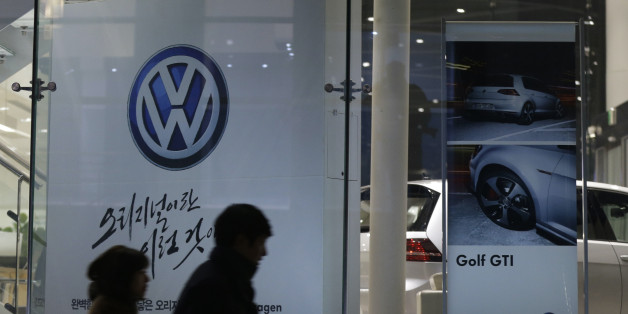 People walk by a logo of Volkswagen at a dealership in Seoul, South Korea, Thursday, Nov. 26, 2015. South Korea said Thursday it fined Volkswagen $12.3 million and ordered recalls of 125,522 diesel vehicles after the government found their emissions tests were rigged. (AP Photo/Ahn Young-joon)