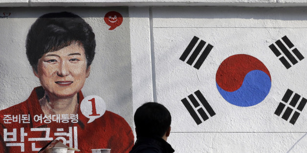A man looks at the wall paintings of South Korea's President-elect Park Geun-hye of ruling Saenuri Party and national flag at Korean Civic Education Institute for Democracy in Seoul, South Korea, Thursday, Dec. 20, 2012. The wall painting is part of renovation work for the building as well as publicizing the 18th Presidential Election which elected Park as the country's first female president. (AP Photo/Lee Jin-man)