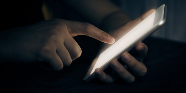 Hand touching digital tablet in darkroom