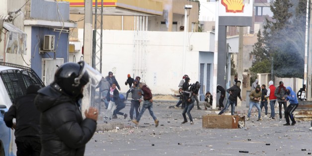 Protesters throw items to police forces in the city of Ennour, near Kasserine, Tunisia, Wednesday, Jan. 20, 2016. Tunisia has declared a curfew in the western city after clashes between police and more than 1,000 young protesters demonstrating for jobs. Tensions have risen in Kasserine since Sunday when an unemployed youth killed himself by scaling an electricity transmission tower to protest his rejection for a government job. (AP Photo/Moncef Tajouri)