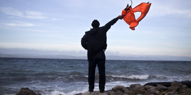 A local man uses a discarded life jacket to signal to an incoming rubber boat filled with migrants and refugees at a beach on the northern coast of Lesbos, Greece, Saturday, Oct. 31, 2015. An official leading rescue efforts on the Greek island of Lesbos has warned that the death toll in the eastern Aegean Sea is likely to rise in the coming days unless urgent action is taken to stop smugglers in nearby Turkey. (AP Photo/Marko Drobnjakovic)