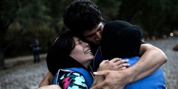 Des gens se réconfortent mutuellement à leur arrivée sur l'île grecque de Lesbos, après une traversée de la mer Egée depuis la Turquie, le 10 septembre 2015