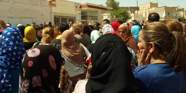Bystanders gather in front of Tunisian Interior Minister Lotfi Ben Jeddou's residence in Kasserine, southern Tunisia, after gunmen attacked the home of the country's top security official killing four of the policeman standing guard outside, Wednesday, May 28, 2014. The attack on Interior Minister Lotfi Ben Jeddou's home in the southern city of Kasserine took place just before midnight and involved six or seven attackers. (AP Photo/Mouldi Kraiem)