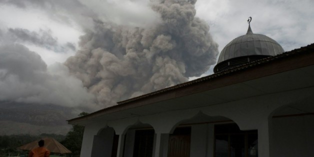 Un Indonésien se tient près d'une mosquée dans le village de Tiga Serangkai dans le nord de Sumatra, le 23 septembre 2015, pendant l'éruption du volcan Sinabung