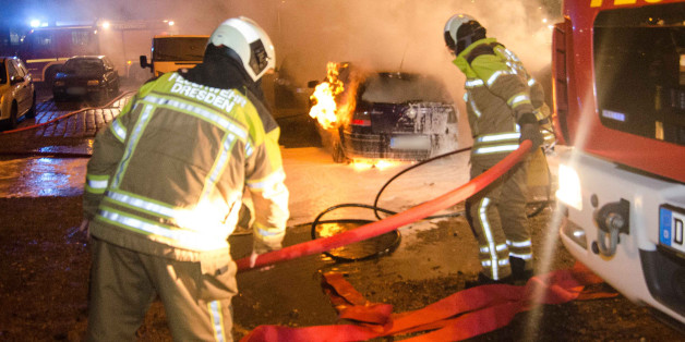 Feuerwehrleute löschen am Rande der Pegida-Demonstration am 25.01.2016 in Dresden brennende Autos.