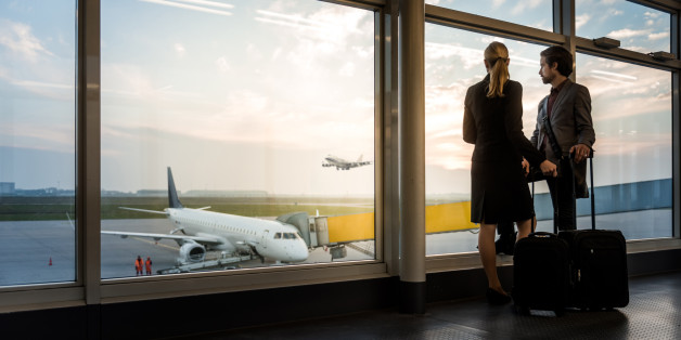 two business travellers standing at airport window and overlooking the airfield