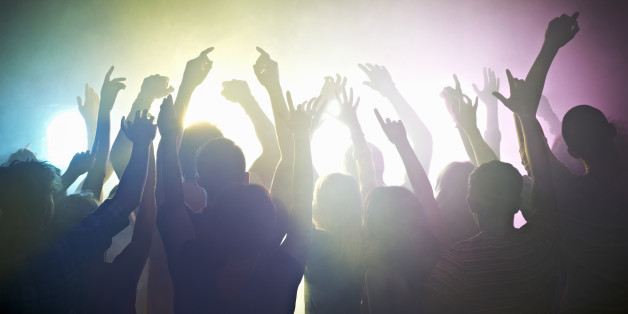 Crowd of people at concert waving arms in the air