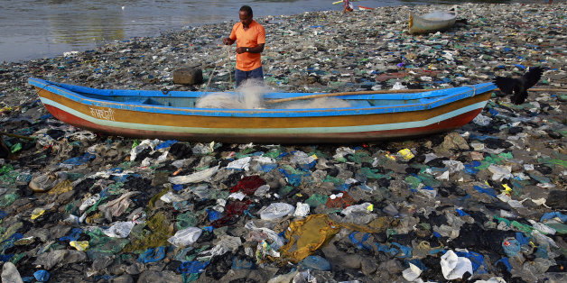 A fisherman prepares his net on the shores of the Arabian Sea, littered with plastic bags, in Mumbai, India, Thursday, Oct. 1, 2015. Thursday marks one year since Indian Prime Minister Narendra Modi launched the "Swachh Bharat Abhiyaan" or "Clean India Mission." (AP Photo/Rafiq Maqbool)
