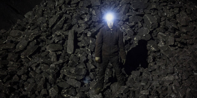 SHANXI, CHINA -NOVEMBER 25: (CHINA, HONG KONG, MACAU, TAIWAN OUT) A Chinese mine worker wears a headlamp as he stands in a pile of coal at a mine on November 25, 2015 in Shanxi, China. A history of heavy dependence on burning coal for energy has made China the source of nearly a third of the world's total carbon dioxide (CO2) emissions, the toxic pollutants widely cited by scientists and environmentalists as the primary cause of global warming. China's government has publicly set 2030 as a deadl