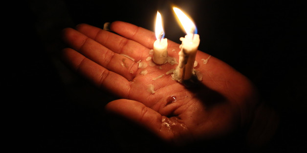 In this Tuesday, April 15, 2015 photo, a Yazidi woman holds candles to make a wish for the new year at the holy shrine of Lalish, 57 kilometers (35 miles) north of militant-held Mosul, Iraq, as thousands gather to mark the holiday, which is their first since Islamic State militants swept through the area last summer. The Yazidis said this year there is hardly any joy as the celebrations are overshadowed by the persecution of Yazidis by the Islamic State group. (AP Photo/Bram Janssen)