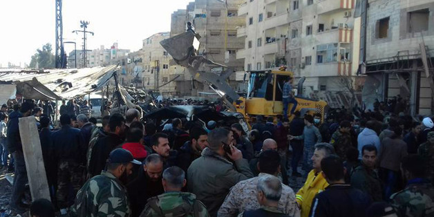 In this photo released by the Syrian official news agency SANA, Syrians gather where three bombs exploded in Sayyda Zeinab, a predominantly Shiite Muslim suburb of the Syrian capital, Syria, Sunday, Jan. 31, 2016. The triple bombing claimed by the extremist Islamic State group killed at least 45 people near the Syrian capital of Damascus on Sunday, overshadowing an already shaky start to what are meant to be indirect Syria peace talks. (SANA via AP)