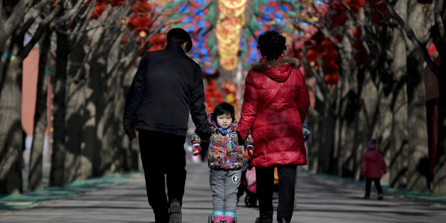 A Chinese elderly couple holds a child standing on a scooter as they walk under colorful decorations for a temple fair ahead of the Chinese Lunar New Year at Ditan Park in Beijing, Tuesday, Feb. 2, 2016. Chinese will celebrate the Lunar New Year on Feb. 8 this year which marks the Year of Monkey on the Chinese zodiac. (AP Photo/Andy Wong)