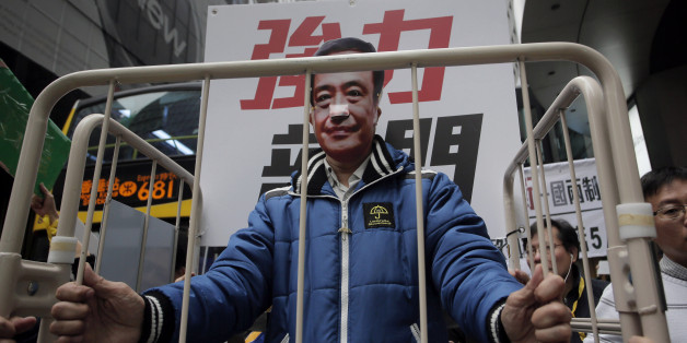 FILE - In this Jan. 10, 2016 file photo, a protester wearing a mask of missing bookseller Lee Bo sits in a cage during a protest against the disappearances of booksellers in Hong Kong. The wife of the missing chief editor of a publisher specializing in books banned in mainland China has told police she has been able to visit him on the mainland, Hong Kong police said Sunday, Jan. 24. It is the latest twist in the disappearances of British citizen Lee and four of his colleagues that have intensif