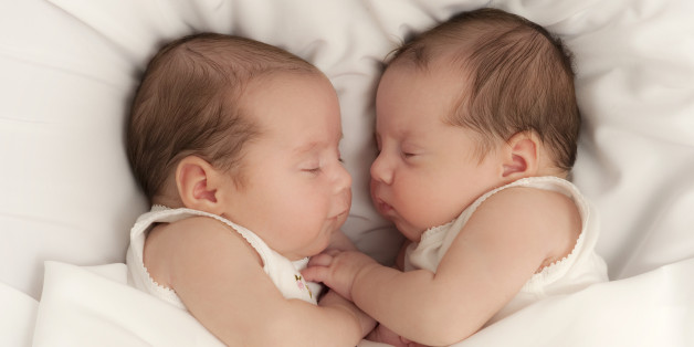 7 week newborn baby girls lie face to face asleep in white background