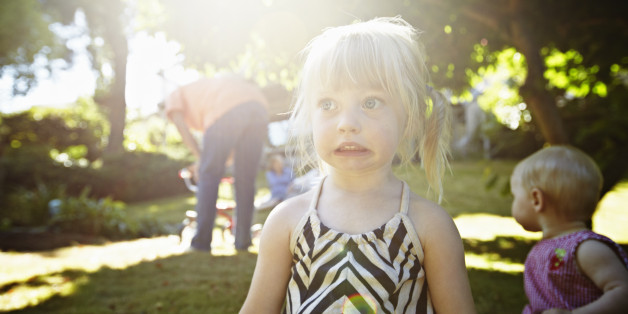 Young girl playing on grass in backyard with baby sister