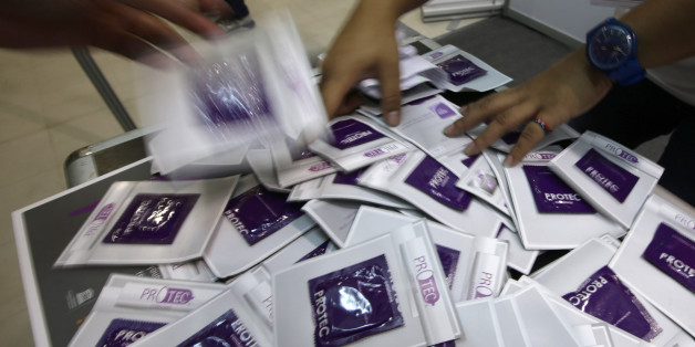 Health workers distributes free condoms to students at one of the booths of the United Nations Population Fund during a day-long activity at a shopping mall to mark World Population Day Friday, July 11, 2014 at suburban Mandaluyong northeast of Manila, Philippines. The World Population Day is marked with lectures on reproductive health care and handing contraceptives to help increase awareness to the growing world population. (AP Photo/Bullit Marquez)