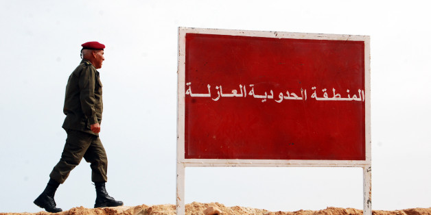 A Tunisian soldier walks on a sandbank near a board saying "no-man's land, buffer zone" during a presentation of the anti-jihadi fence, in near Ben Guerdane, eastern Tunisia, close to the border with Libya, Saturday, Feb. 6, 2016. Tunisia's defense minister has visited an anti-jihadi fence that's being built on the country's border with Libya to stop Islamist militants from entering Tunisian territory. Defense Minister Farhat Horchani inspected the first completed part of the 196-kilometer (122-