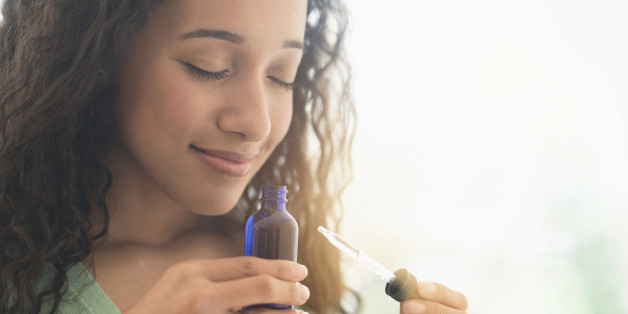 Close up of mixed race woman smelling aromatherapy oil