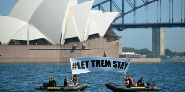 Des militants de Greenpeace brandissent une banderole avec l'inscription "#LET THEM STAY" ("#Laissez les rester") devant l'opéra de Sydney, le 14 février 2016, alors qu'un hôpital australien refuse de renvoyer un bébé dans un camp de réfugiés controversé