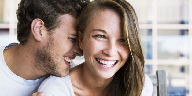 Young seated couple laughing intimately