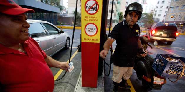A motorcyclist pays about two Bolivars (3 cents of a dollar) after filling his scooter's tank at a gas station in Caracas, Venezuela, Wednesday, Feb. 17, 2016. Venezuelaâs government is raising gasoline prices sixtyfold, the first increase of any kind in more than 17 years as the country struggles with an economic collapse. Yet drivers will still be able to fill their tanks for pennies. (AP Photo/Fernando Llano)