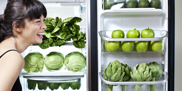 Mixed race woman looking at green vegetables in refrigerator