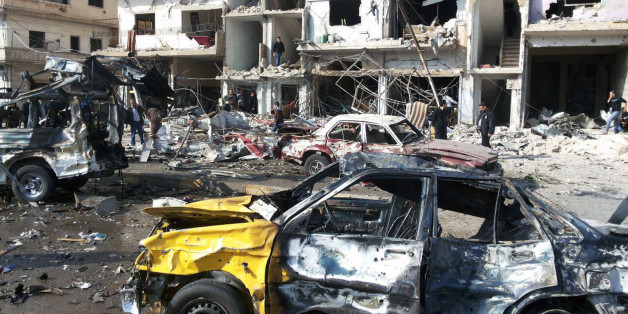 In this photo released by the Syrian official news agency SANA, Syrian citizens gather at the scene where two blasts exploded in the pro-government neighborhood of Zahraa, in Homs province, Syria, Sunday, Feb. 21, 2016. Two blasts in the central Syrian city of Homs killed more than a dozen people and injured many others in the latest wave of violence to hit the city in recent weeks, state TV said. (SANA via AP)