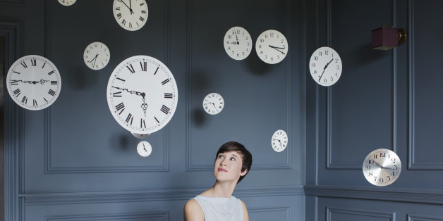 Woman in armchair with hanging clocks above