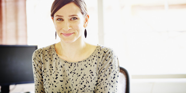 Smiling female businesswoman seated at workstation