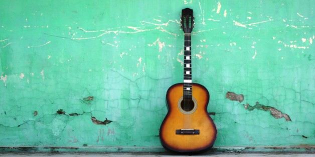 Eine Gitarre lehnt an einer Hauswand