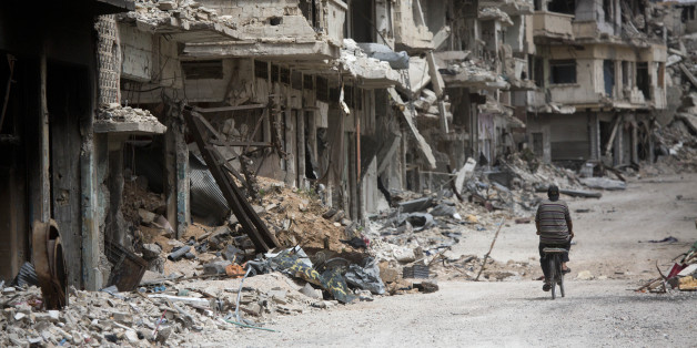 FILE - In this June 5, 2014 file photo, a man rides a bicycle through a devastated part of Homs, Syria. (AP Photo/Dusan Vranic, File)