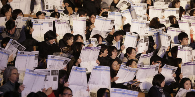 Students and their parents check lists of colleges during a presentation by a private educational academy on how to select the right college for this year's college entrants at Jamsil gymnasium in Seoul, South Korea, Thursday, Dec. 3, 2015. Results of the College Scholastic Aptitude Test came out on Dec. 2, and applicants need to find the colleges they qualify for depending on their test scores. (AP Photo/Ahn Young-joon)