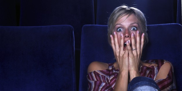 Blond woman in movie theater viewing horror film