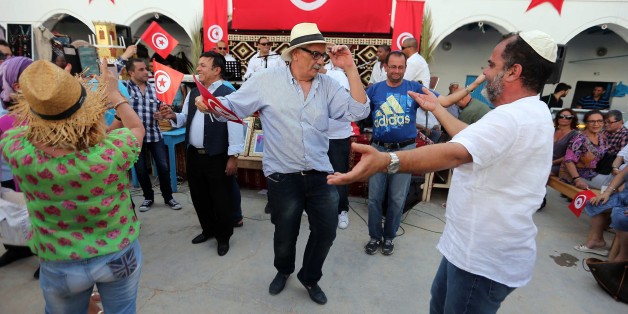 Jewish pilgrims dance and chant during a ceremony at the Ghriba synagogue in the resort of Djerba, south Tunisia, Wednesday, May 6, 2015. Jews coming from Tunisia, Europe or Israel make their annual pilgrimage to El Ghriba synagogue, commemorating the death of Shimon Bar Yohai, a second-century kabbalistic rabbi who authored a famous religious text known as The Zohar. The Tunisian flag is seen on background. (AP Photo/Mohsen May)