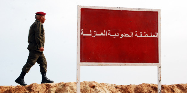A Tunisian soldier walks on a sandbank near a board saying "no-man's land, buffer zone" during a presentation of the anti-jihadi fence, in near Ben Guerdane, eastern Tunisia, close to the border with Libya, Saturday, Feb. 6, 2016. Tunisia's defense minister has visited an anti-jihadi fence that's being built on the country's border with Libya to stop Islamist militants from entering Tunisian territory. Defense Minister Farhat Horchani inspected the first completed part of the 196-kilometer (122-